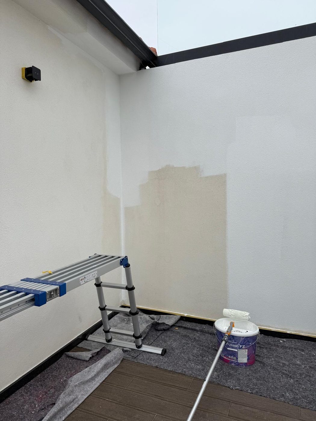 Parede de terraço a ser pintada a rolo, com pavimento protegido