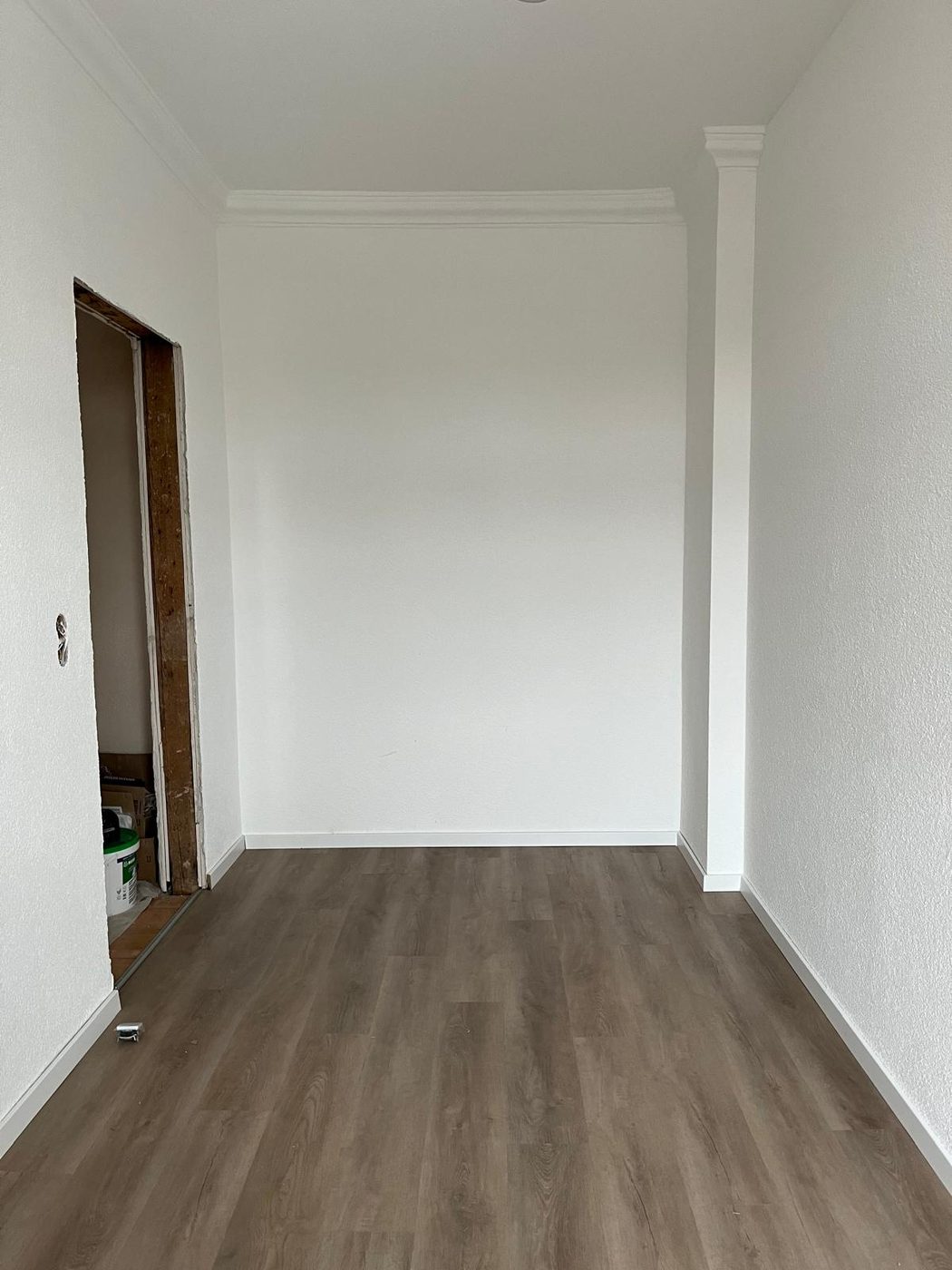Sala com paredes brancas e pavimento vinílico colocado